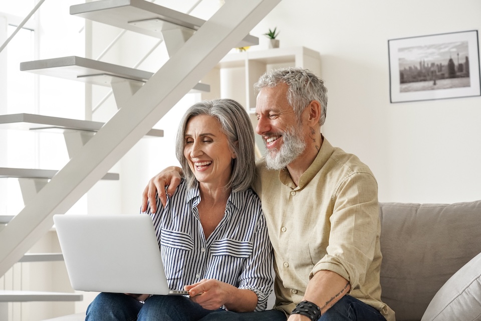 Older couple sitting on couch using a laptop together