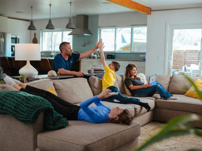 man high fiving child on couch with family surrounding