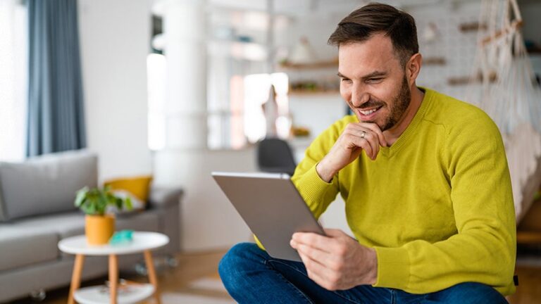 man smiling and holding tablet