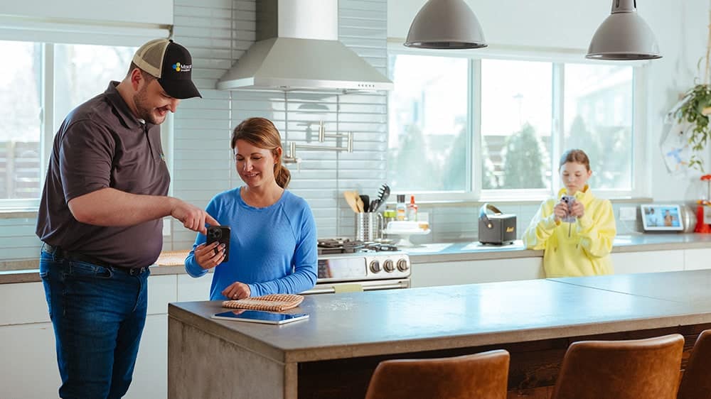 Mercury service technician with woman standing in kitchen explaining fiber and home internet services