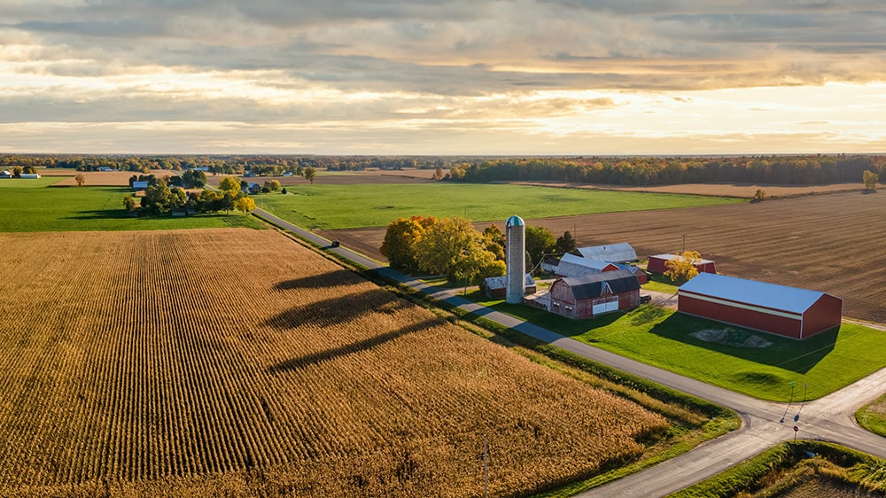 sunset rural landscape scene with farm in foreground