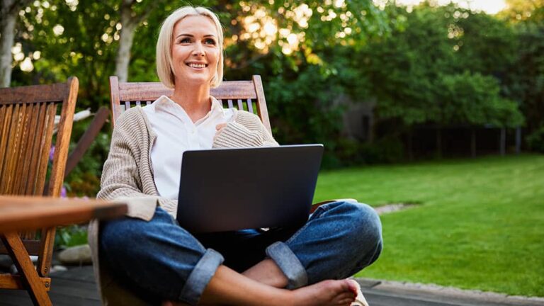 woman smiling sitting outside with laptop computer