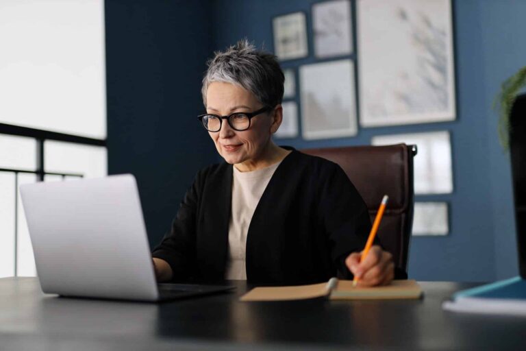 happy woman sitting at desk looking at laptop