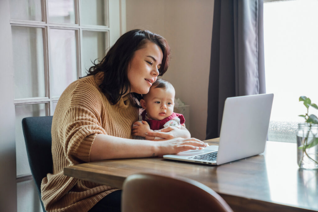 woman with infant sitting at laptop computer