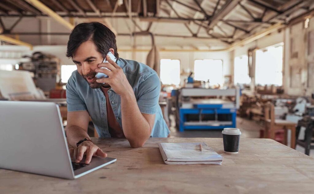 man working at laptop in workshop setting