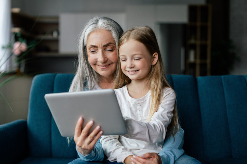 woman and child sitting on couch looking at tablet