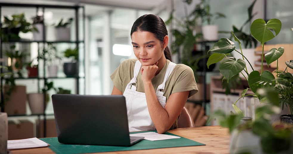 A Woman working at a plant shop using a laptop