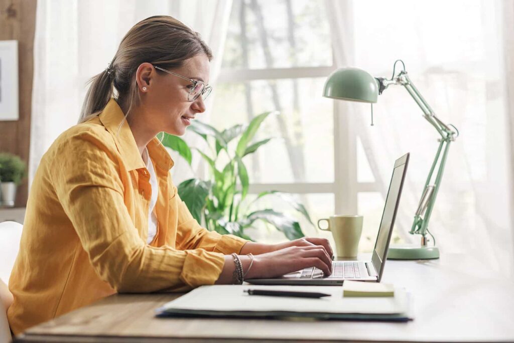 A woman with glasses working on her laptop