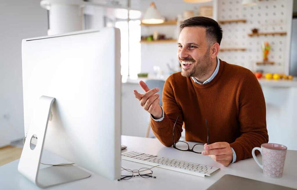 A man smiling while working on his desktop