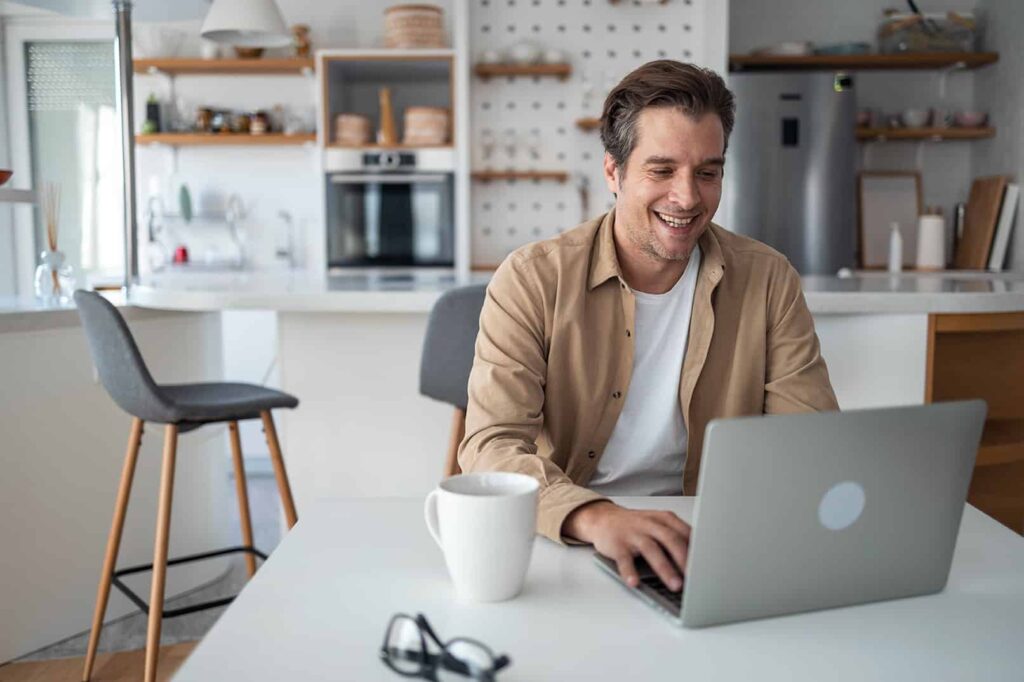 A man smiling while working on his laptop