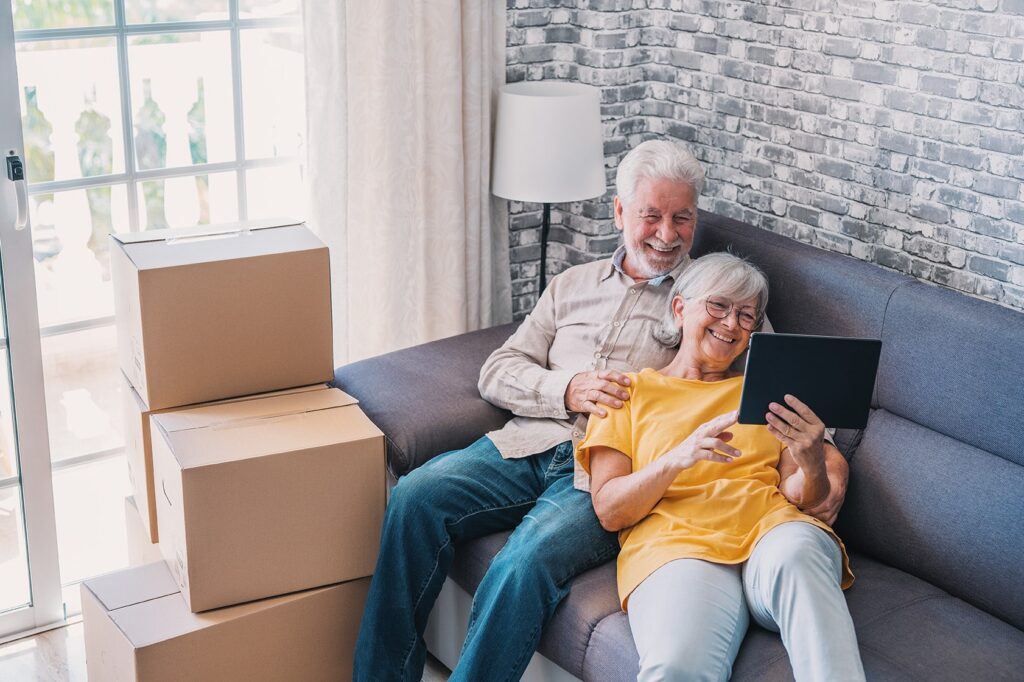 A elder couple who just moved into their new home on their laptop on their couch