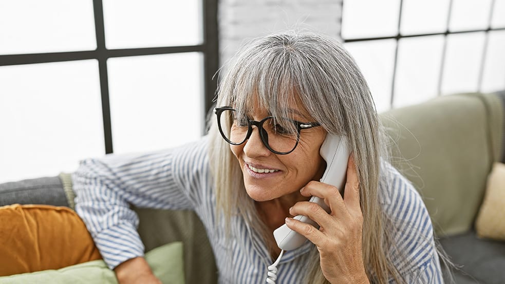 elderly woman talking on landline phone