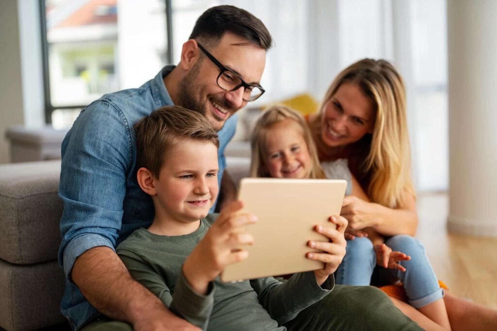 family of 4 sitting with tablet looking together
