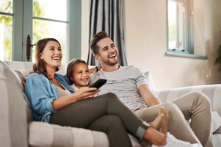 smiling family on couch with tv remote
