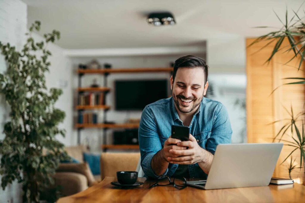 man sitting with phone and computer