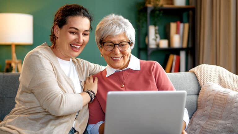 middle aged woman helping older woman on her laptop